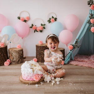 bambina che festeggia il primo compleanno con la torta in un servizio fotografico
